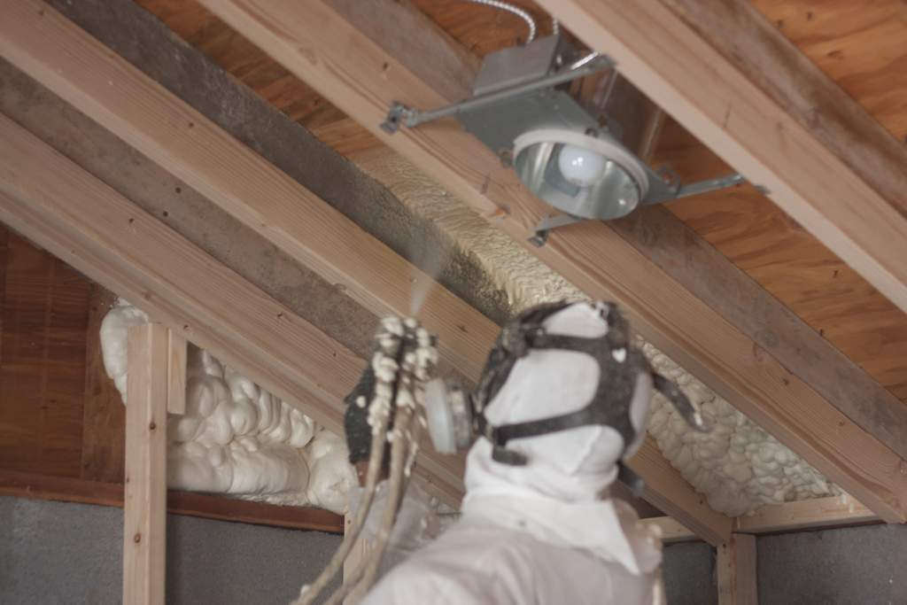 A person spraying foam insulation inside a building